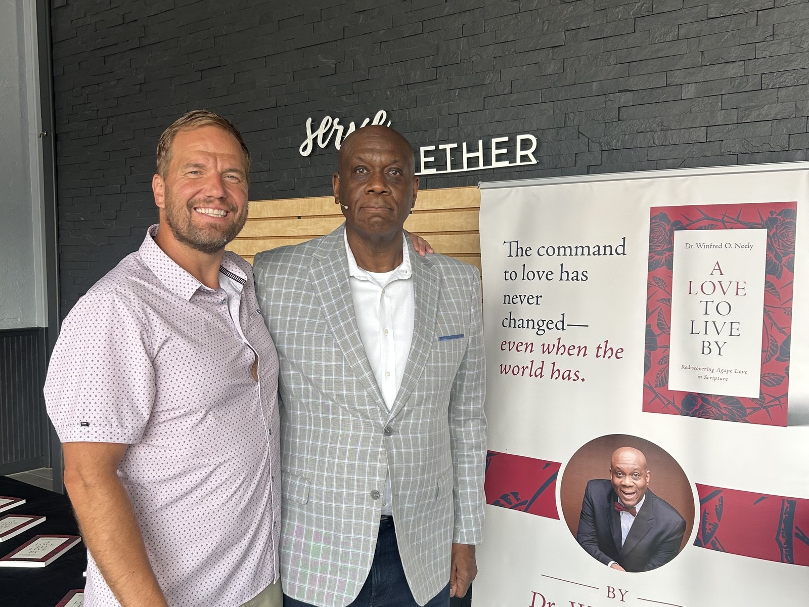 Dr. Neely at an A Love to Live By book-signing event beside the book's display banner